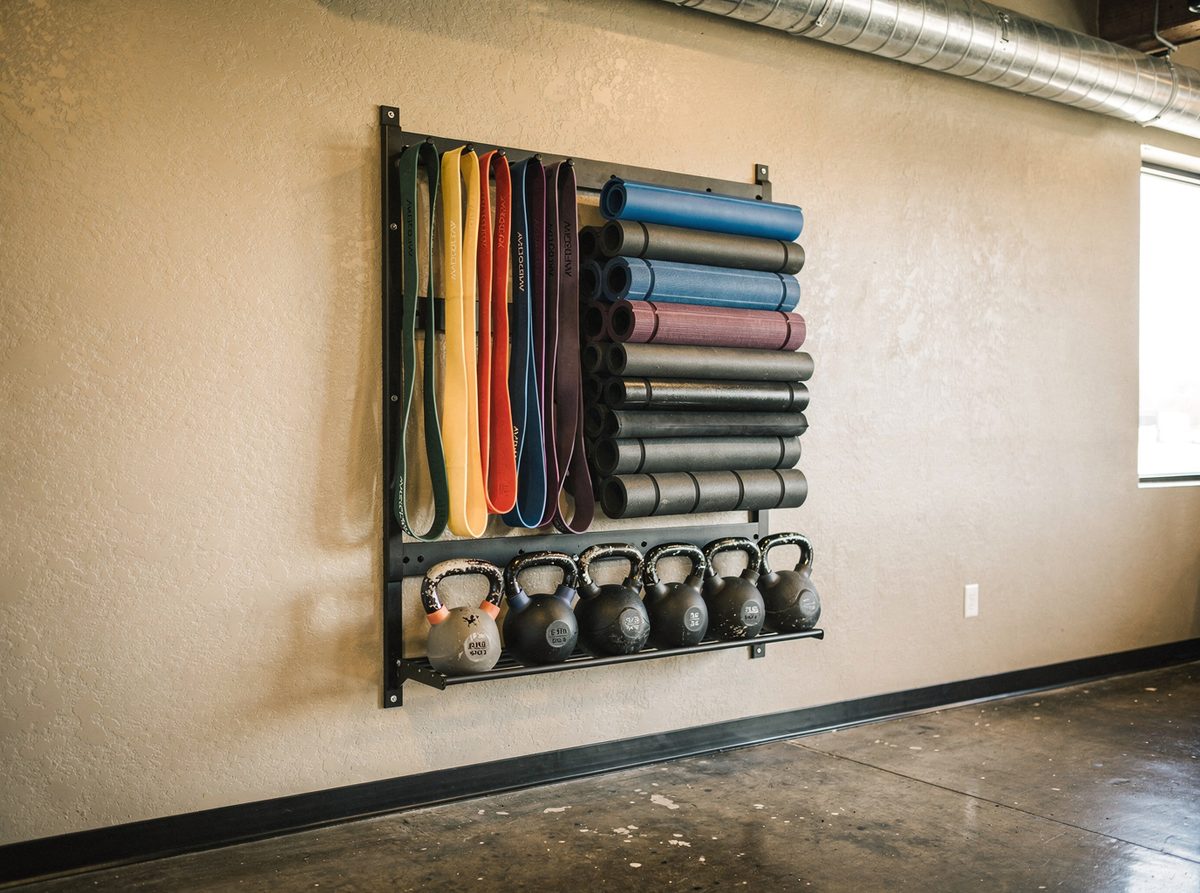 Resistance bands, foam rollers and kettlebells organized on a studio equipment rack